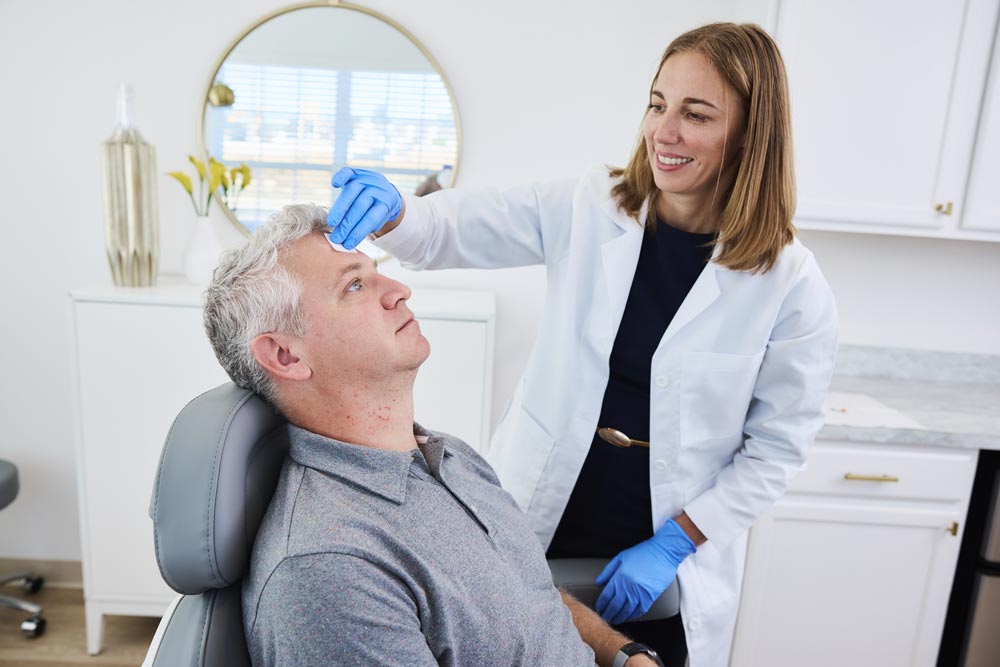 Dr. Jacques prepares male patient for Botox injections in glo MD treatment room.