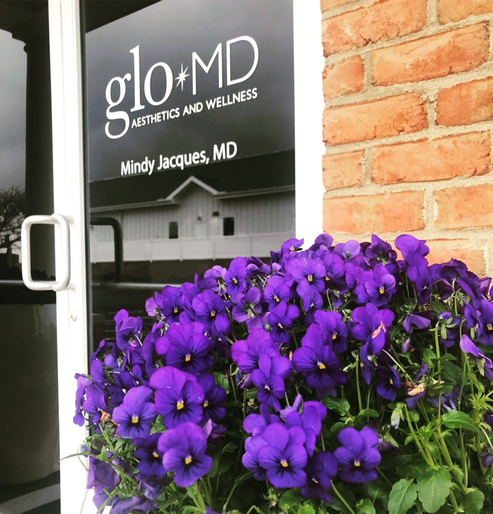 Purple pansies in flower pot outside door of glo MD Aesthetics and Wellness in Powell, OH