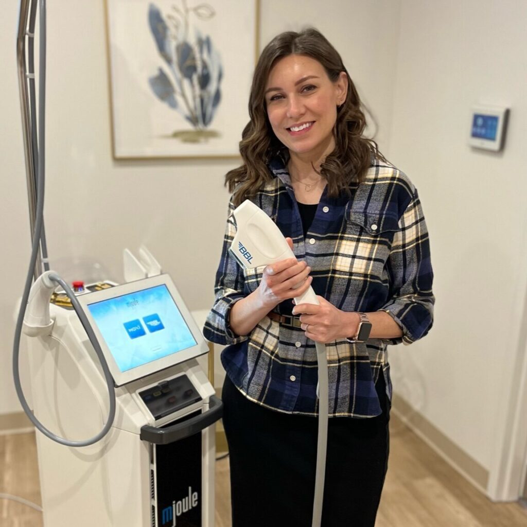 Eve Suiter, LPN, LE stands with laser hair removal machine in treatment room.